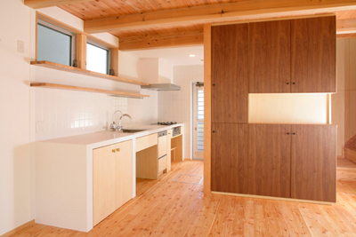 オリジナルキッチンと造作食器棚。白いタイルの壁と濃い目の木目のコントラスト。建具のつまみはアンティーク雑貨